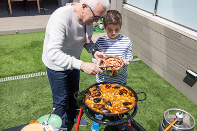 Grandfather and grandson preparing a paella in the garden