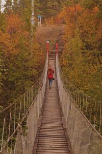 Rear view of man walking on footbridge