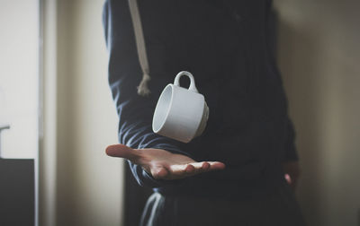 Close-up midsection of man catching cup at home