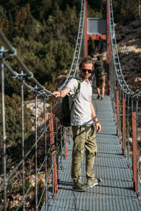 Traveler with a backpack in the mountains. a middle-aged man stands on a suspension bridge 