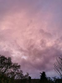 Low angle view of silhouette trees against dramatic sky