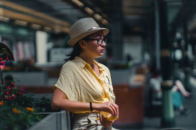 Young woman wearing sunglasses standing against blurred background