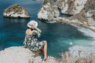 Woman sitting on rock by sea