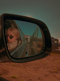Reflection of man photographing on side-view mirror