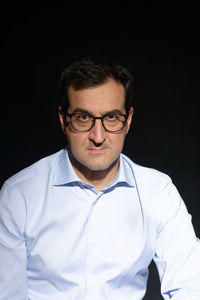 Portrait of young man wearing eyeglasses against black background