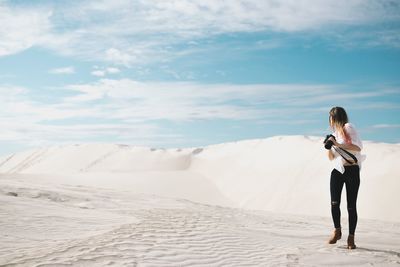 Woman standing on sand dune at beach