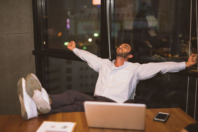 Businessman relaxing by laptop at office