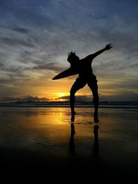 Silhouette man jumping on shore at beach during sunset - sky