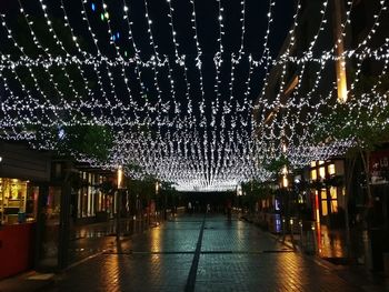 Illuminated lights on footpath in city at night