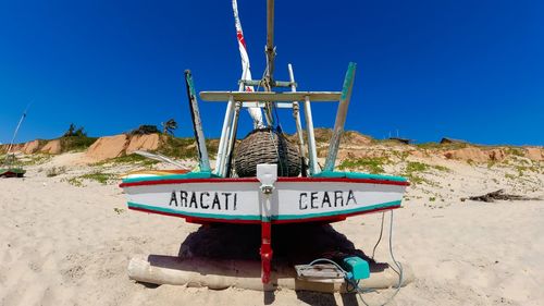 Information sign on beach against clear blue sky