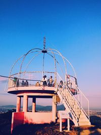 People on lookout tower against clear blue sky