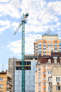 Tower crane against the background of a modern multi-storey residential building under construction.