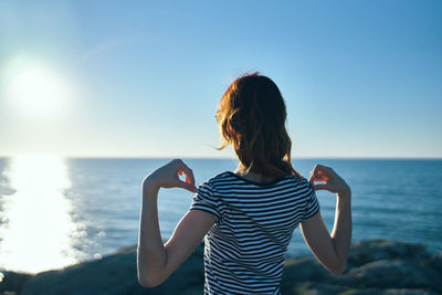 Woman standing at beach against sky