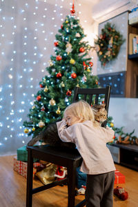 Rear view of girl decorating christmas tree at home