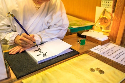 Midsection of man reading book on table