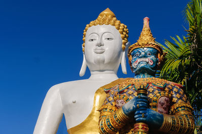 Low angle view of statue against blue sky and building