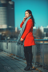 Woman standing by railing in city