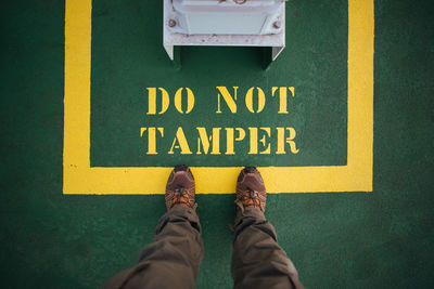 Low section of man standing on yellow sign