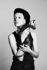 Young woman with cat standing against gray background