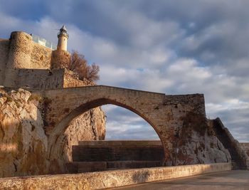 Arch bridge over building against sky