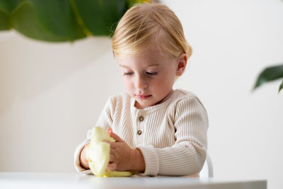 Portrait of cute girl sitting at table playing with slime 