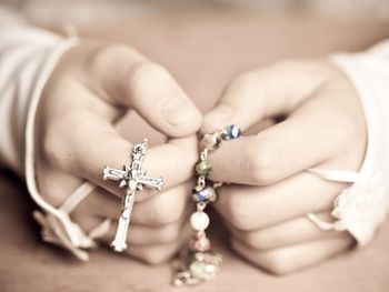 Cropped hands of woman holding rosary