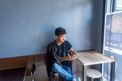 Young man using mobile phone while sitting in cafe