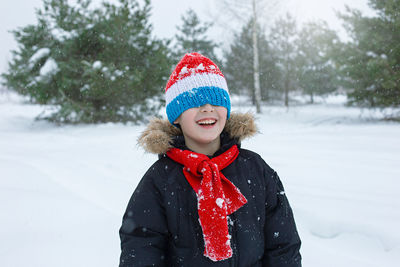 Happy boy in bright winter clothes and a red scarf