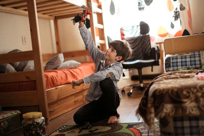 Boy teen plays with designer on the floor in real children's room