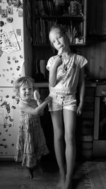 Portrait of girl with sister eating popsicles while standing at home 
