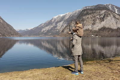 Father and son enjoying mountains, snow, lake, good weather, blue sky, sun. 