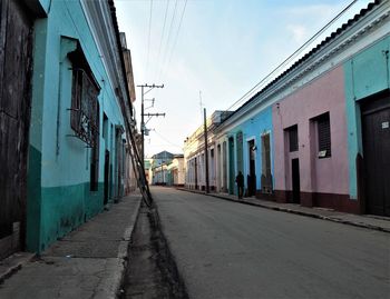 Empty road amidst buildings against sky