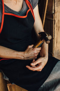 Hands of female carpenter holding hammer and mallet, close up