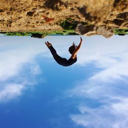 Low angle view of woman jumping against clear sky