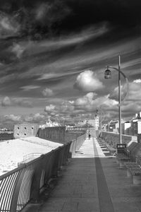 Walkway against cloudy sky