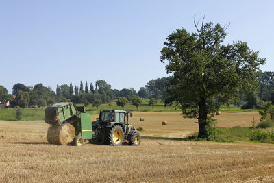 Agricultural machinery on agricultural field against clear sky