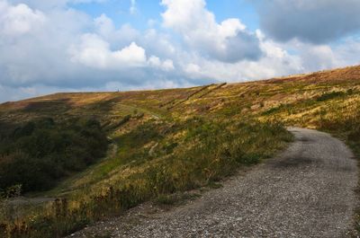 Road amidst field against sky