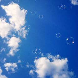 Low angle view of bubbles against cloudy sky