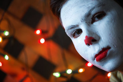 Close-up portrait of boy with face paint against illuminated light