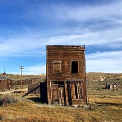 Abandoned house on field against sky