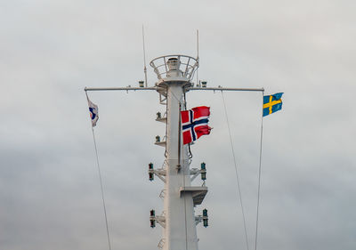 Low angle view of flags hanging on pole against sky