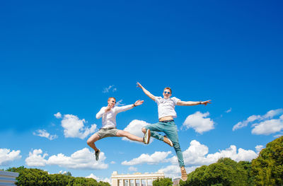 Low angle view of man jumping against sky