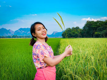 Happy woman standing on field against sky