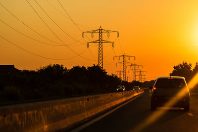 Illuminated street against sky during sunset
