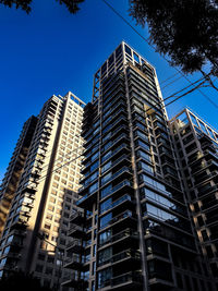 Low angle view of modern buildings against blue sky