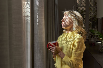 Side view of a woman looking through window