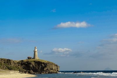 Lighthouse by sea against sky