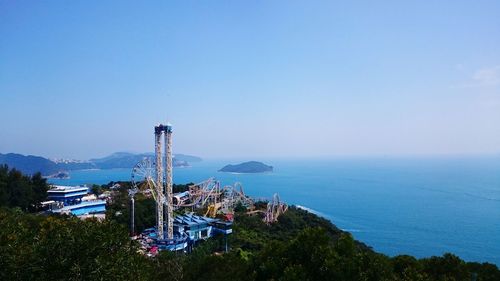 High angle view of amusement park by sea against clear sky