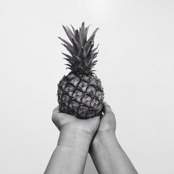 Close-up of hands holding fruit against white background