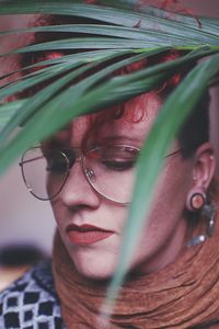 Close-up of woman wearing eyeglasses seen through plant